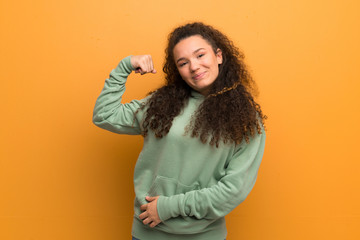 Teenager girl over ocher wall doing strong gesture