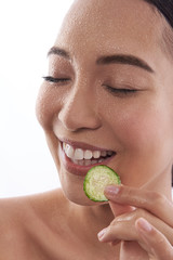 Happy lady with wet face holding cucumber slice