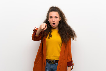 Teenager girl with coat surprised and pointing front