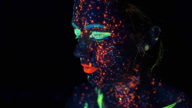portrait of a young woman painted with luminous paints. neon paint on the girl's face.