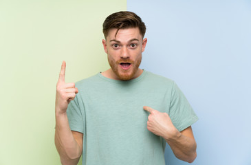 Redhead man over colorful background with surprise facial expression