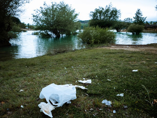 Plastic bag and trash left in the shore of a swamp