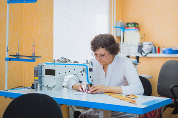 Professional tailor, fashion designer sewing clothes with sewing machine at atelier, studio. Fashion and tailoring concept