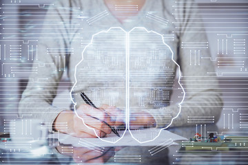 Double exposure of writing hand on background with brain hologram. Concept of learning.