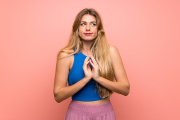 Young blonde woman over isolated pink background scheming something