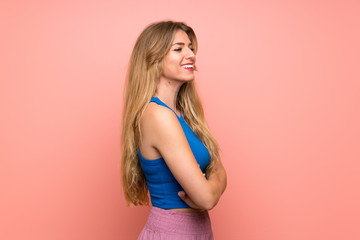 Young blonde woman over isolated pink background in lateral position