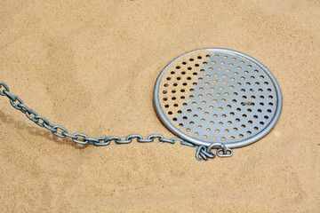 Iron sieve on chain for sifting sand in childrens sandbox for children.