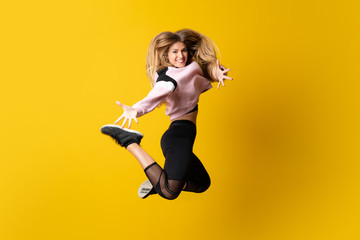 Urban Ballerina dancing over isolated yellow background and jumping