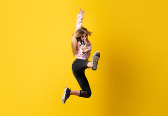 Fototapeta na wymiar Urban Ballerina dancing over isolated yellow background and jumping