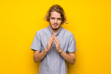 Blonde man over isolated yellow background scheming something