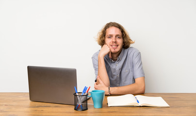 Blonde man with a laptop laughing