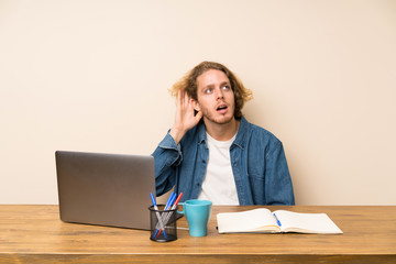 Blonde man with a laptop listening something