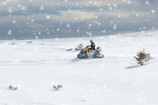 Athlete on a snowmobile moving in the winter forest in the mountains