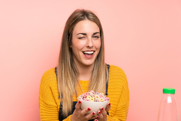 Happy Young woman with bowl of cereals over pink wall