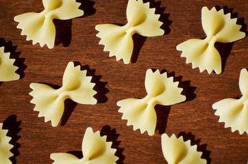 Pasta in a shape of bow isolated on wooden background, macaroni background,photo