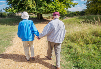 Elderly couple holding hands while visiting the British countryside.