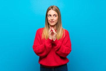 Woman with red sweater over blue wall scheming something