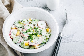 Fresh summer salad with cucumbers, radishes, eggs with cream fresh dressing