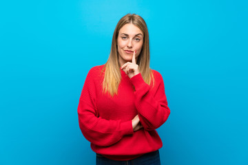 Woman with red sweater over blue wall Looking front