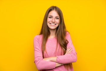Obraz premium Young woman with long hair over isolated yellow wall keeping the arms crossed in frontal position