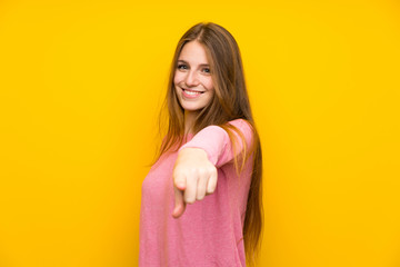 Obraz premium Young woman with long hair over isolated yellow wall points finger at you with a confident expression