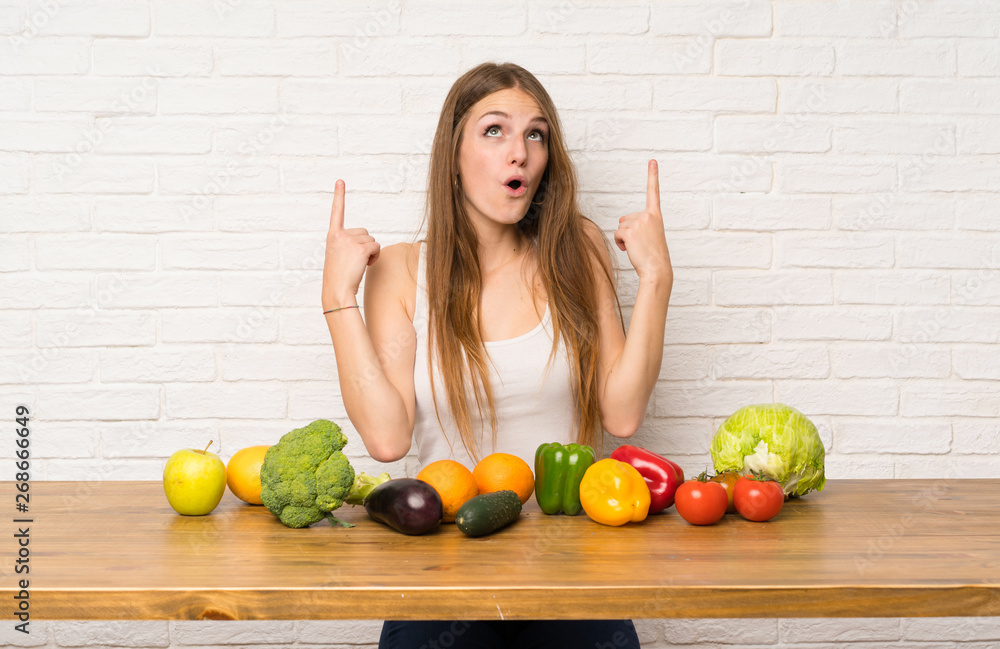 Wall mural young woman with many vegetables pointing with the index finger a great idea