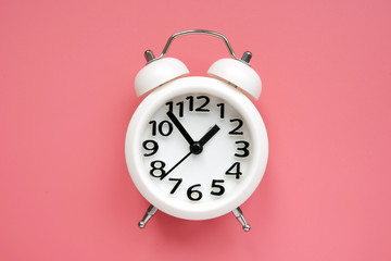 White alarm clock on a pink surface.