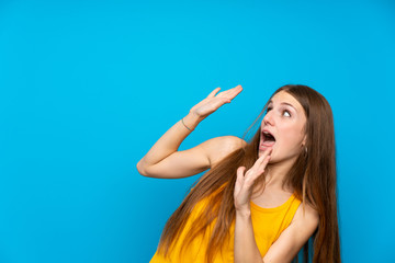 Young woman with long hair over isolated blue wall nervous and scared