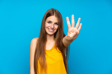 Young woman with long hair over isolated blue wall happy and counting four with fingers