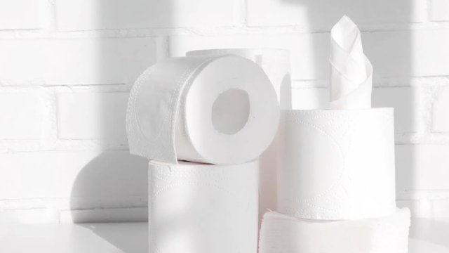 Paper towels, toilet paper and napkins in white loft interior. Paper disposables, hygienic products concept. Slow pan. Selective focus. Closeup.