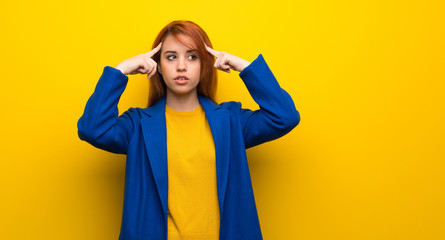 Young redhead woman with trench coat having doubts and thinking