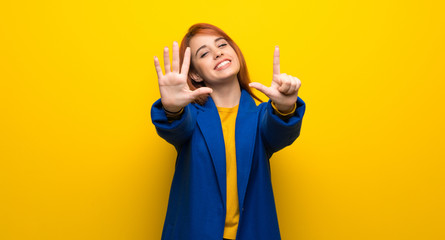 Young redhead woman with trench coat counting seven with fingers