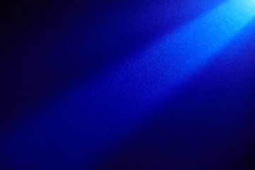 Dark blue beam of light shining from top to bottom on a dark background.