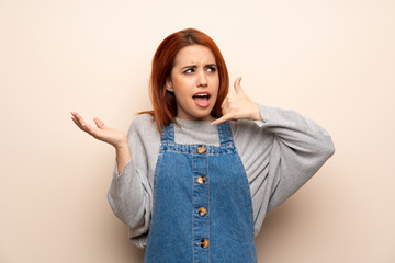 Young redhead woman over isolated background making phone gesture and doubting