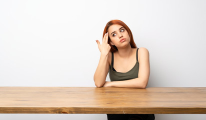 Young redhead woman at desk with problems making suicide gesture
