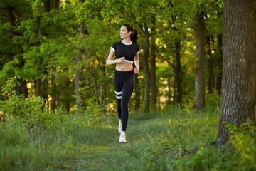 Sexy, sporty girl with a beautiful figure wearing a sports brassiere and leggings, doing sport exercises, outdoor running