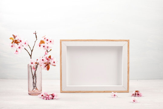 Mock up with empty picture frame and pink spring flowers.