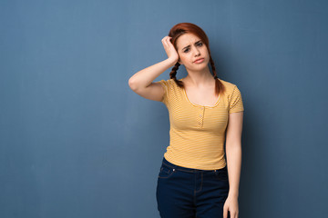 Young redhead woman over blue background with an expression of frustration and not understanding