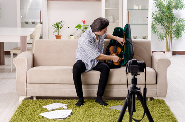Young male blogger playing violin at home   © Elnur