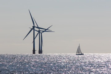 Wind power. Environmentally friendly sailing yacht. Offshore windfarm turbines. Clean energy.