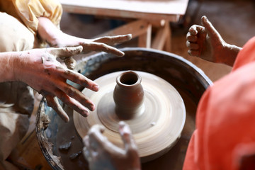 Fototapeta na wymiar Child makes clay pot on potters wheel