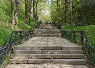 Old stone stairs with metal railing in a city park. View from down