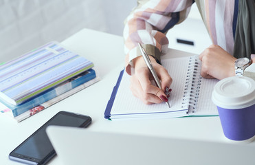 Top view of business woman hands making notes with silver pen in office background. Business finance savings loan and credit concept.