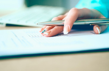 Fototapeta premium Hand of businesswoman filling and signing with silver pen partnership agreement form clipped to pad close-up. Management training course, some important document, team leader ambition concept
