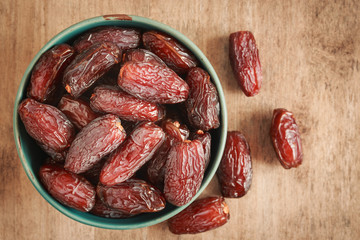 close up picture of dates palm fruit in cup on wooden table background. Dates palm fruit dry is snack healthy.
