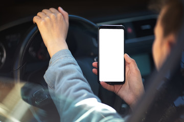 Young girl driving the car with smartphone in hand