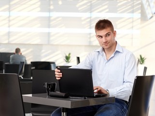 Young rookie businessman working on laptop at cafe