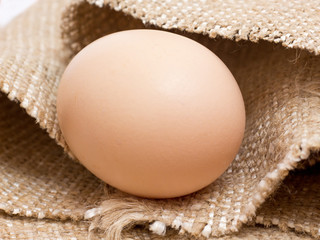 Fresh chicken egg lays on a rough sack_