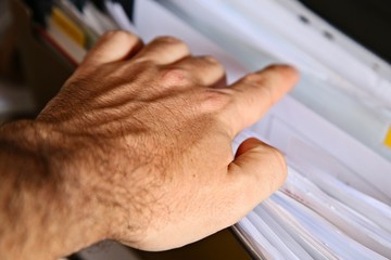 A Caucasian man looking inside a filing cabinet for tax records.  Administration concept image.  