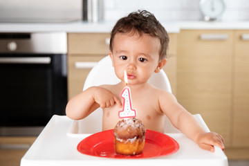 Baby blowing candle on first birthday